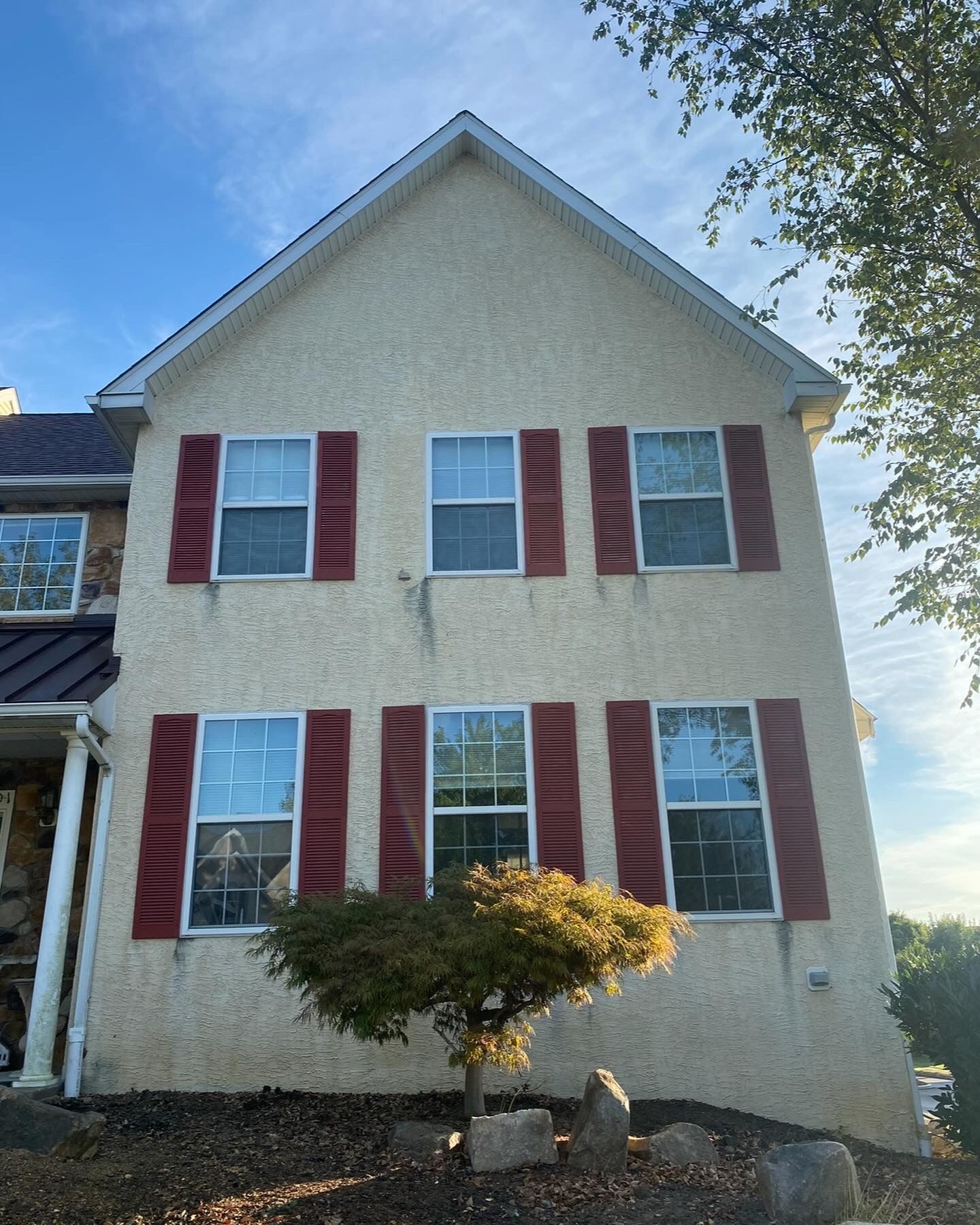 A house with red shutters and a tree in front of it
