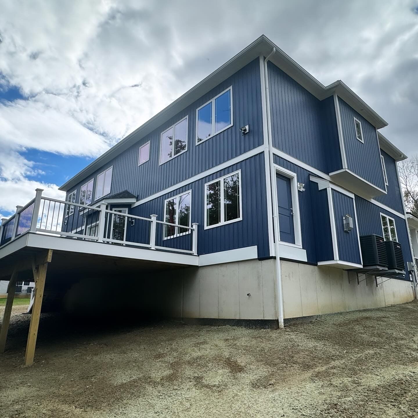 A large blue house with a large deck on the side of it.