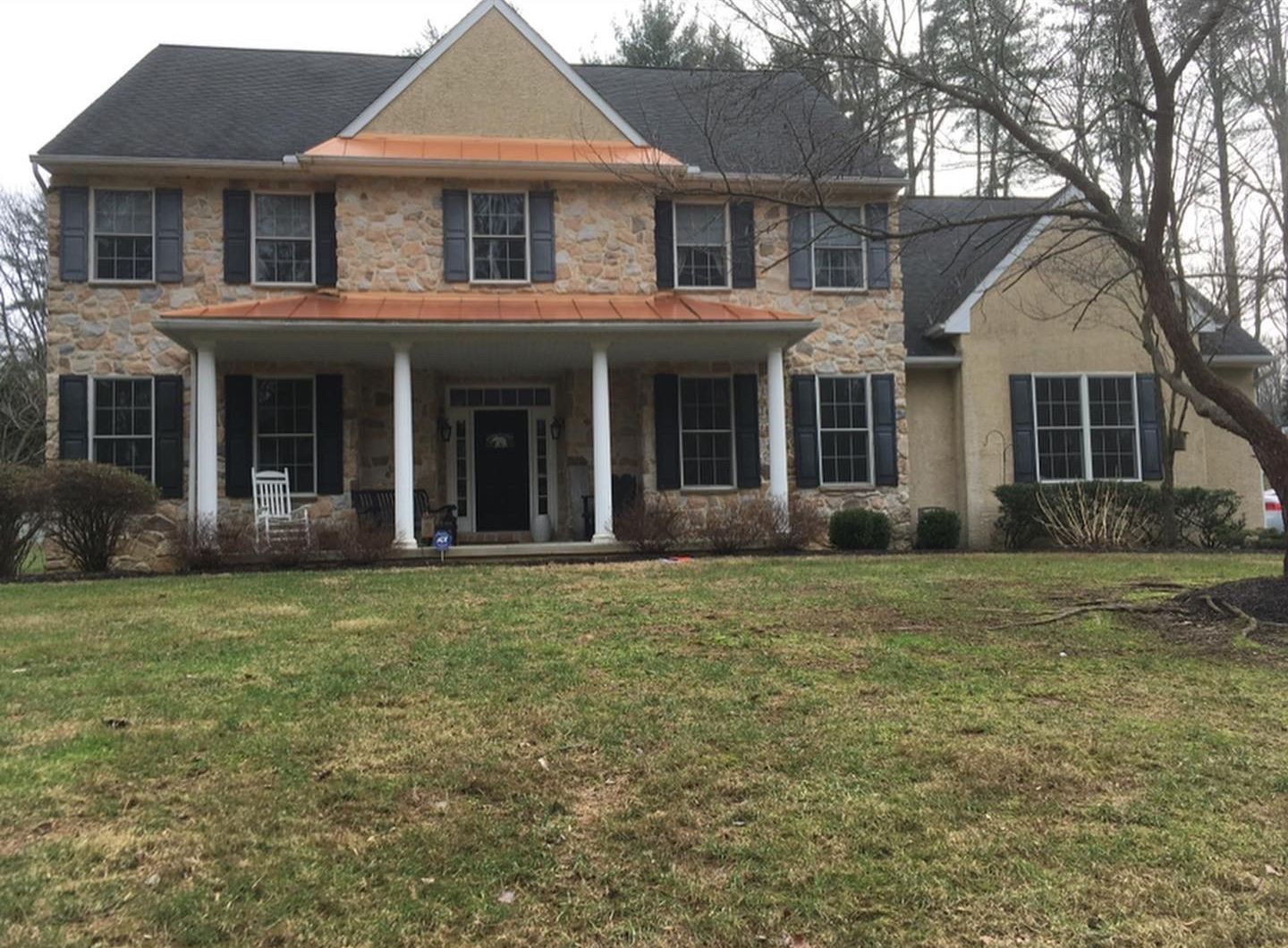A large brick house with a porch and black shutters