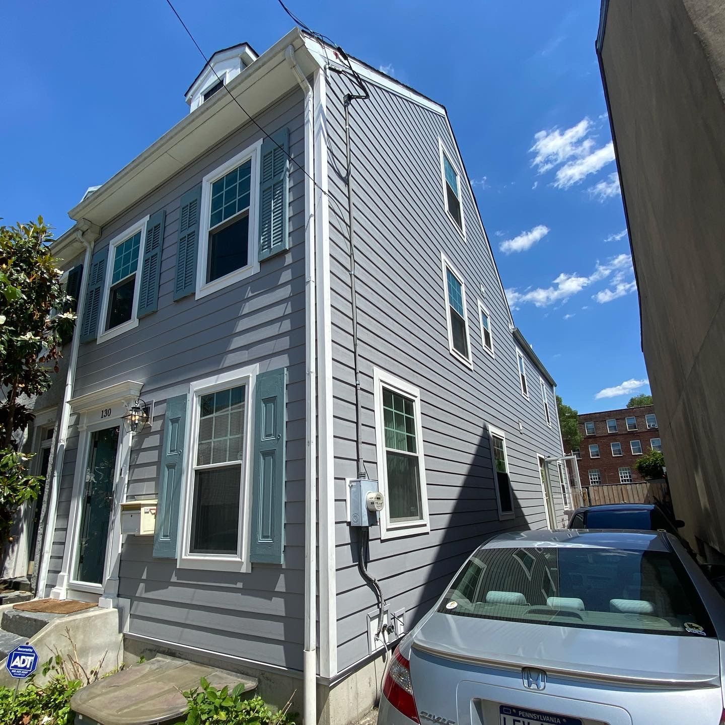 A gray house with a white car parked in front of it.