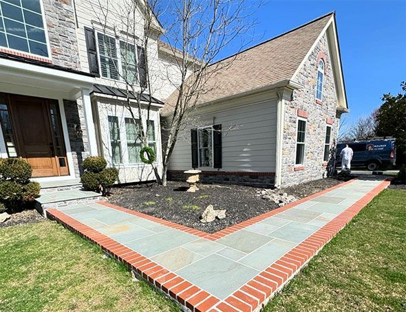 A large white house with a brick walkway in front of it.