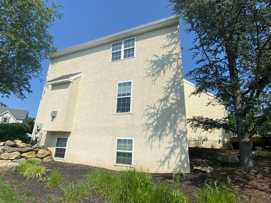 A large white house with a lot of windows is surrounded by trees and grass