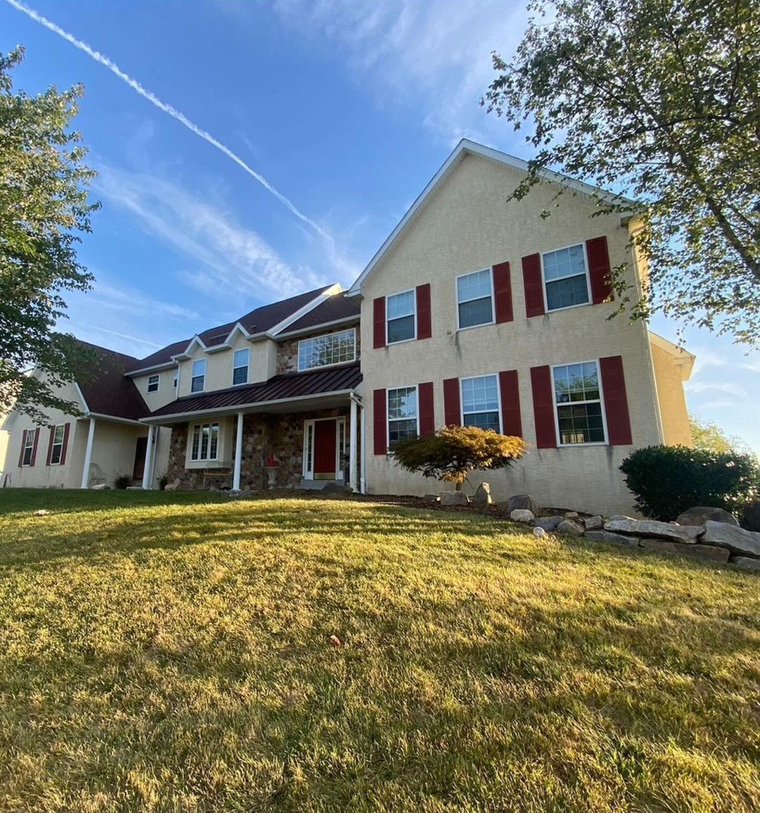 A large house with red shutters and a large lawn in front of it