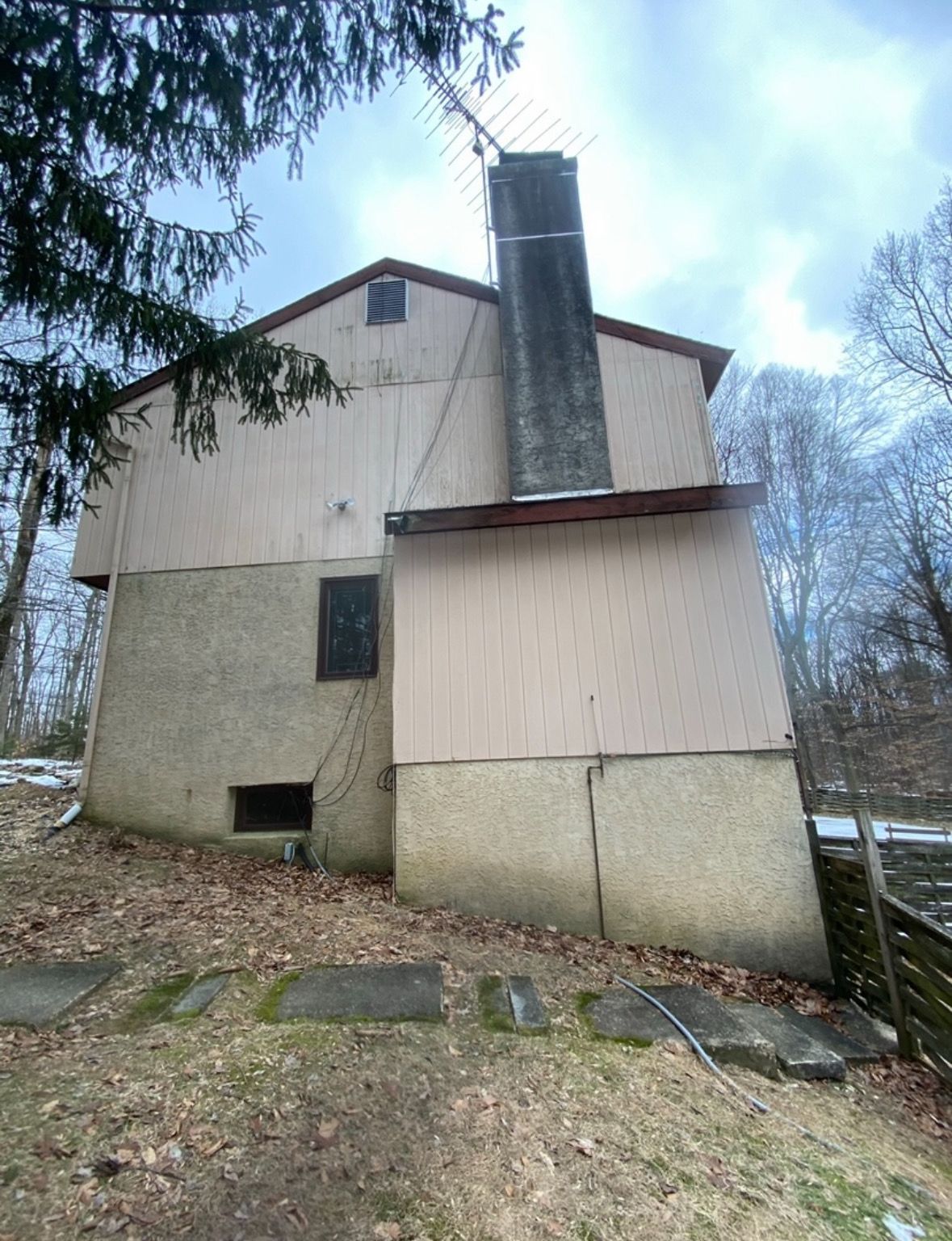 A large house with a chimney on the side of it.