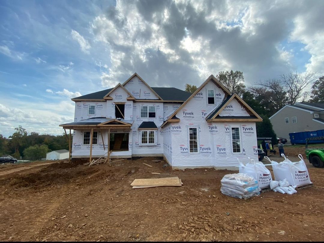 A large house is being built on top of a dirt hill.