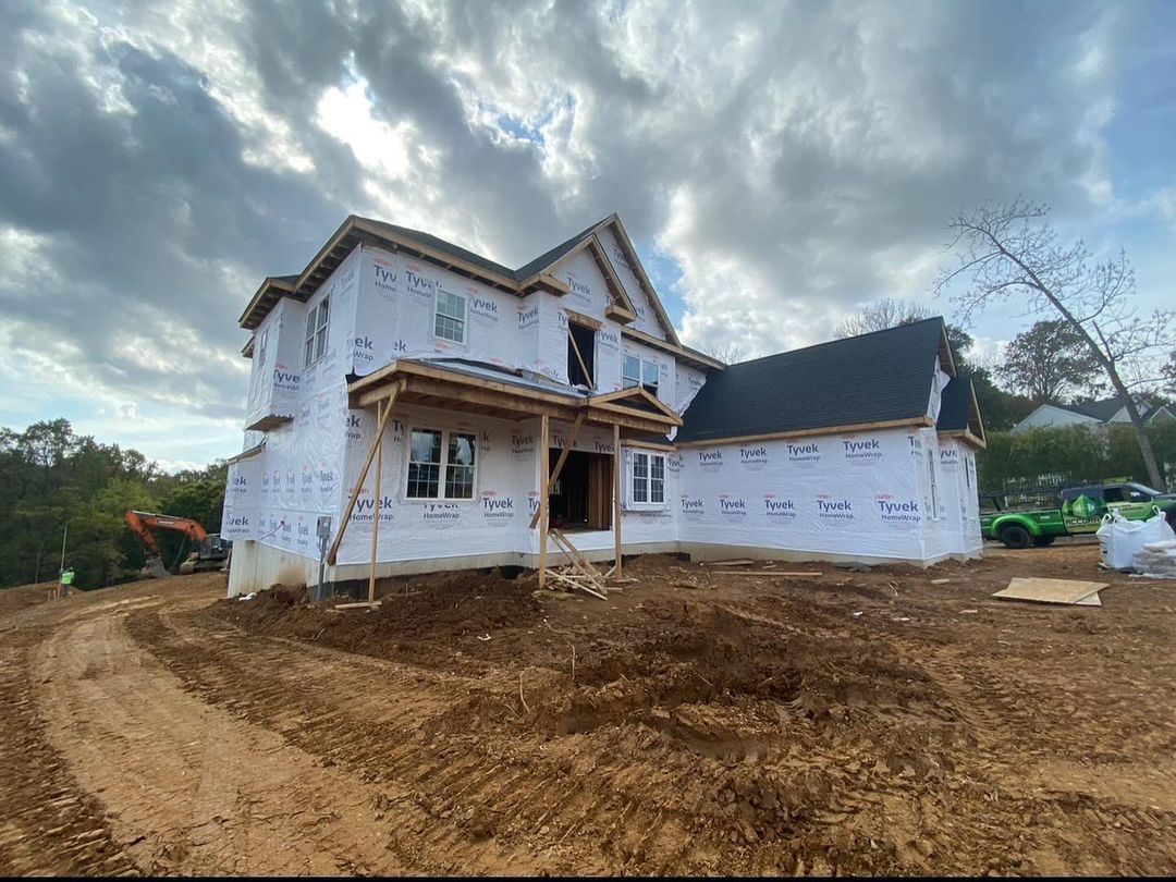 A large house is being built on top of a dirt hill.