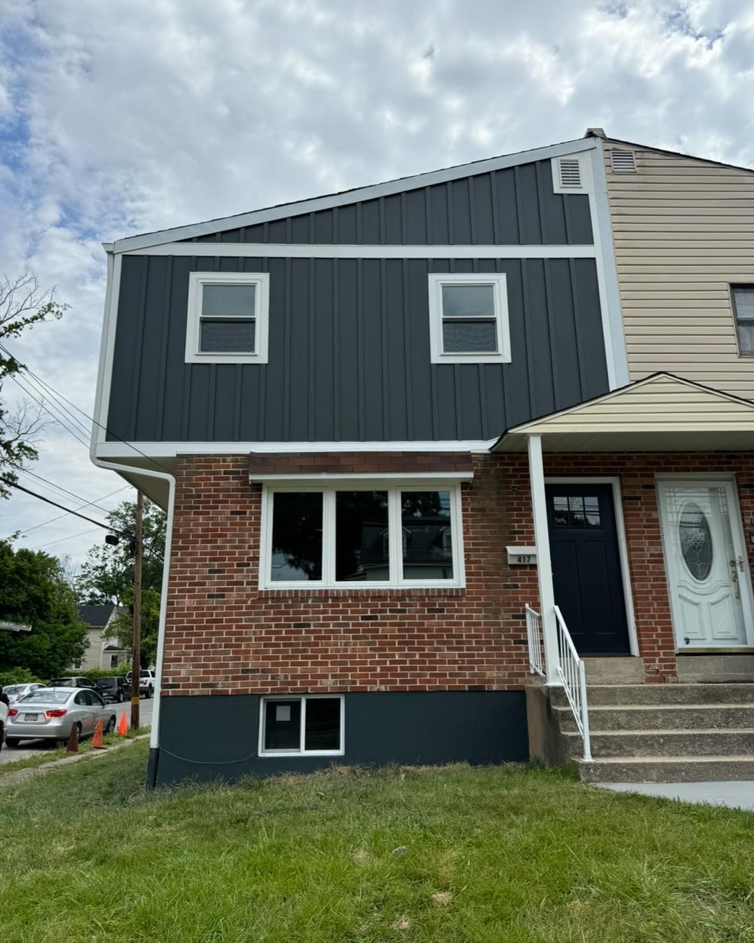 A brick house with a black siding and a black door.