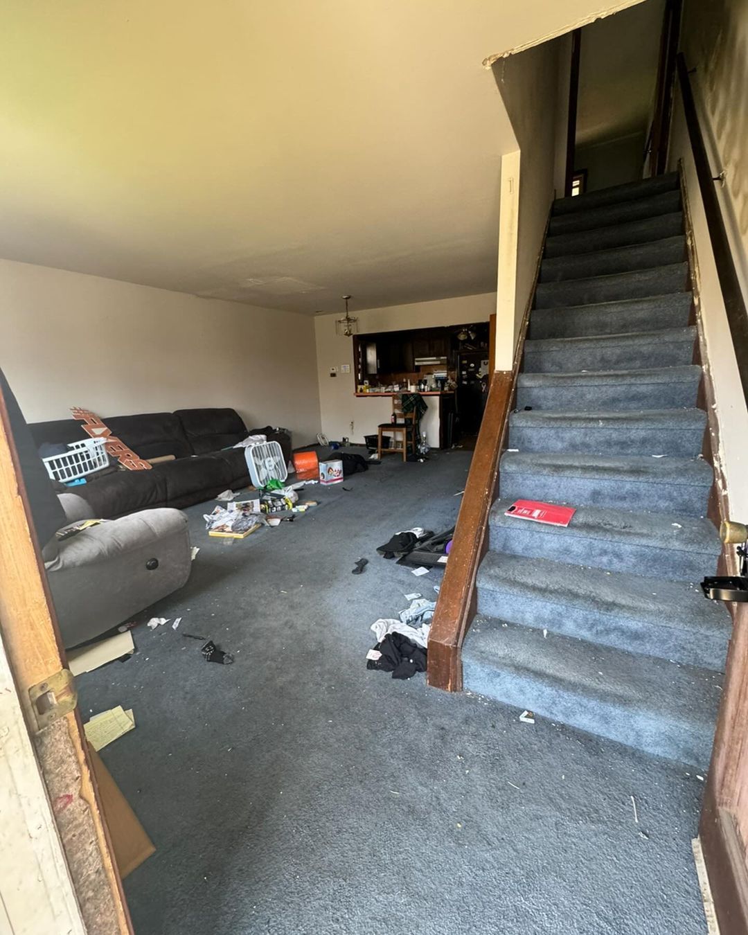 A living room with a couch and stairs leading up to the second floor.