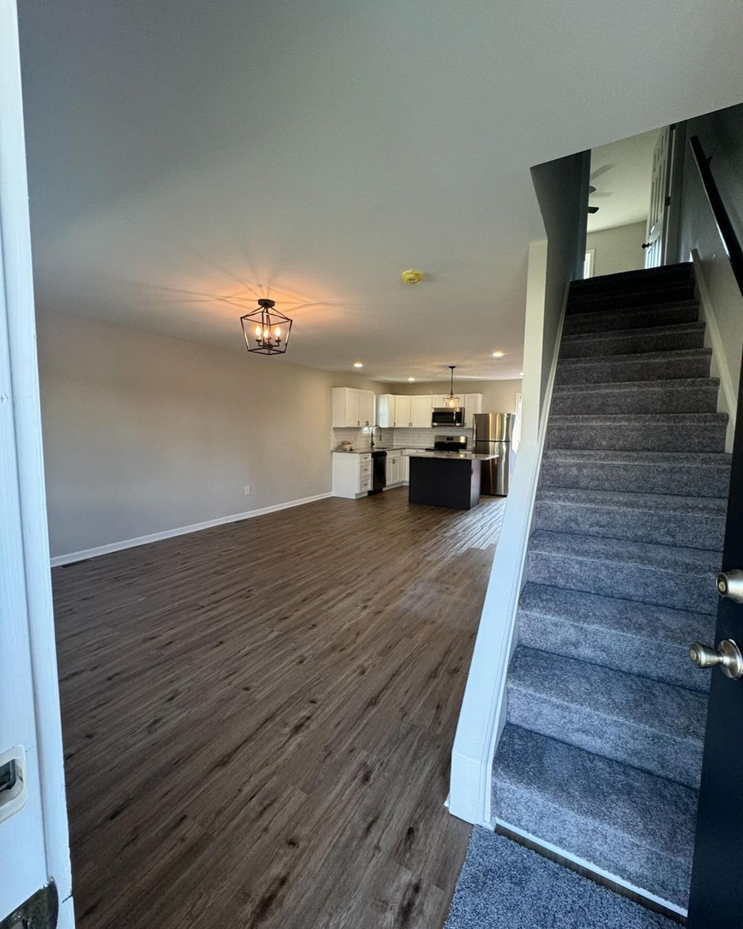 A living room with hardwood floors and stairs leads to the second floor.