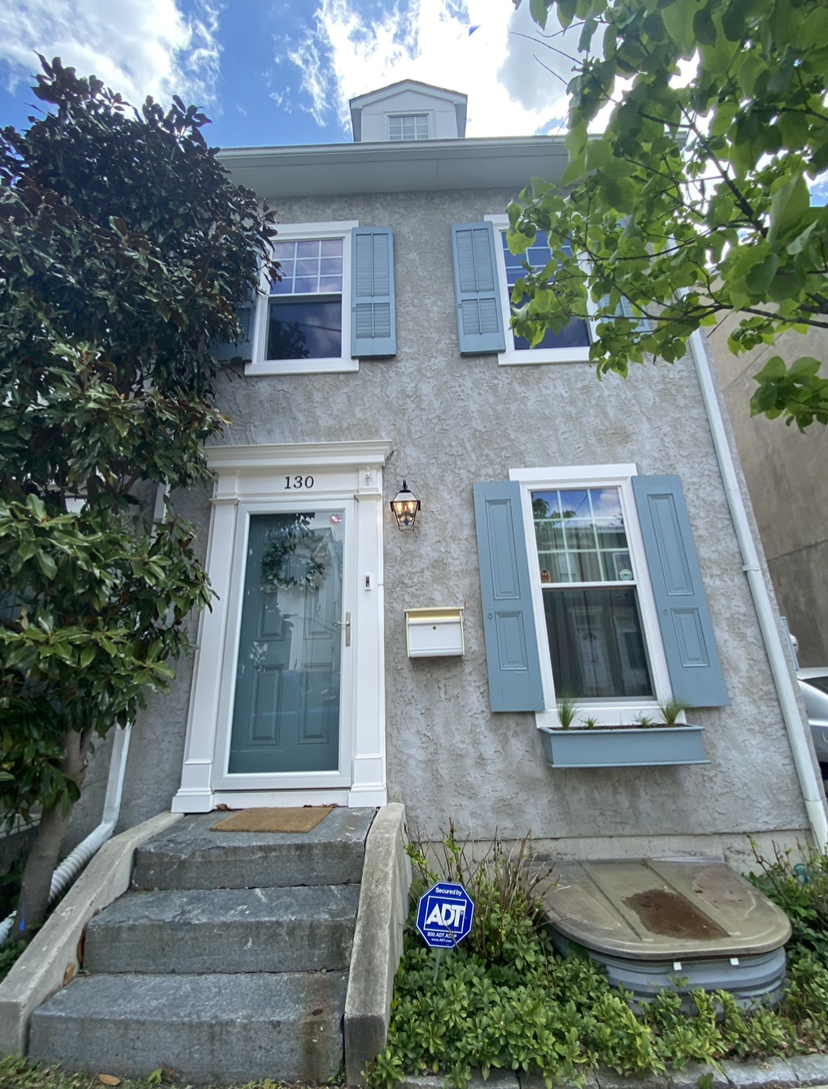 The front of a house with blue shutters and stairs.