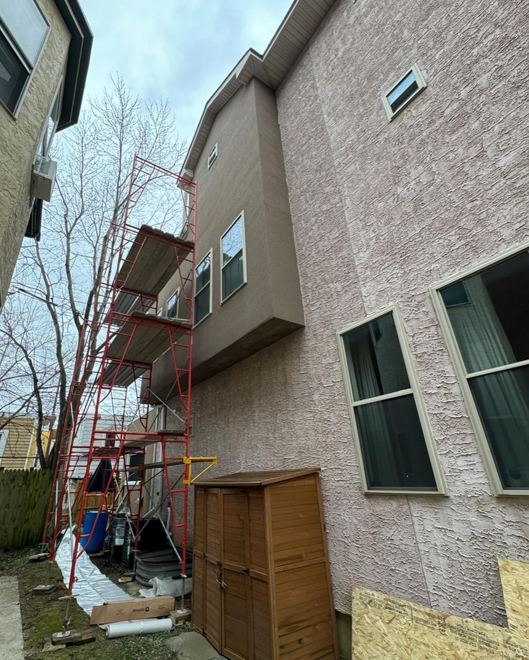 A house with scaffolding on the side of it is being painted.