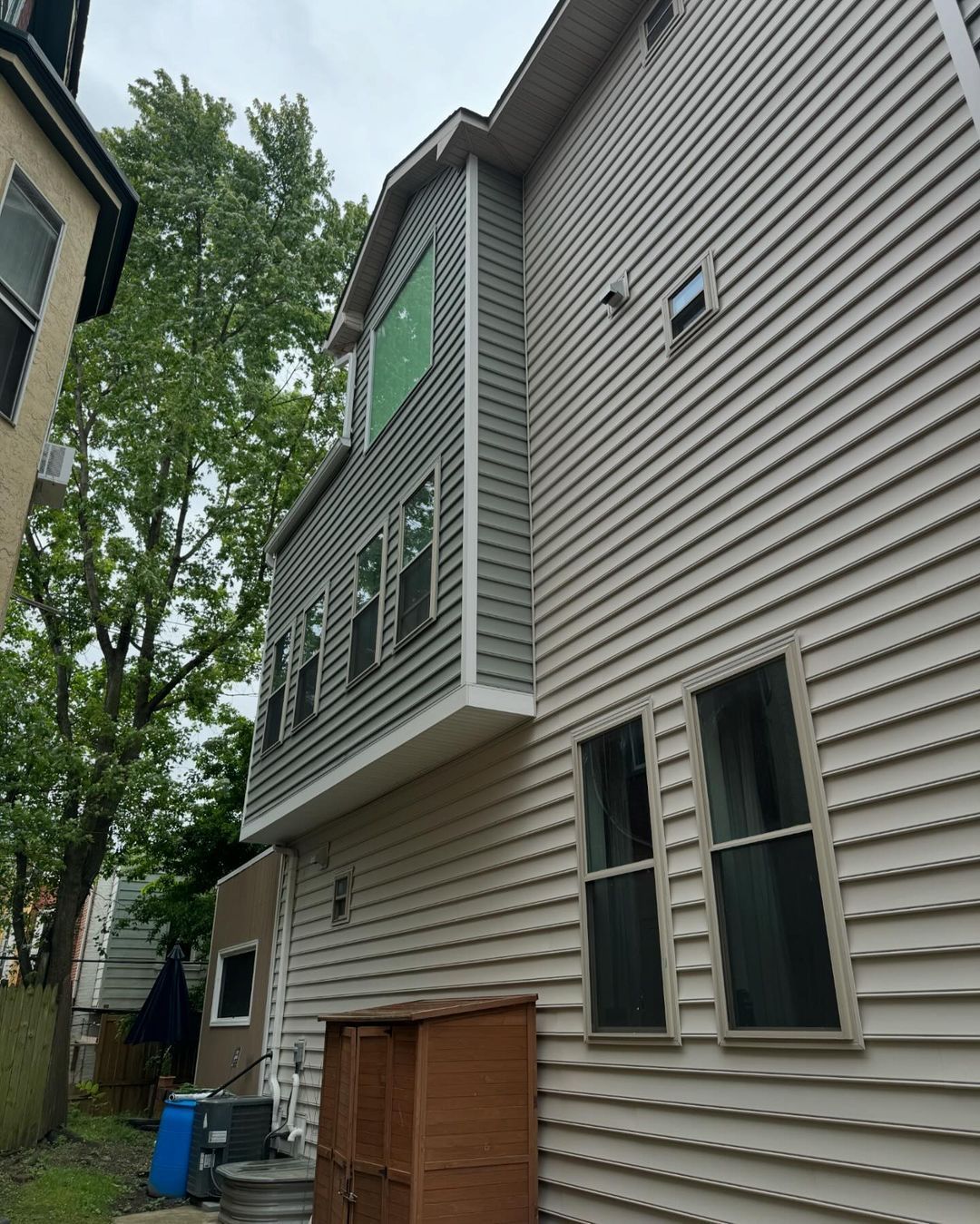 The back of a house has many windows and a green window.