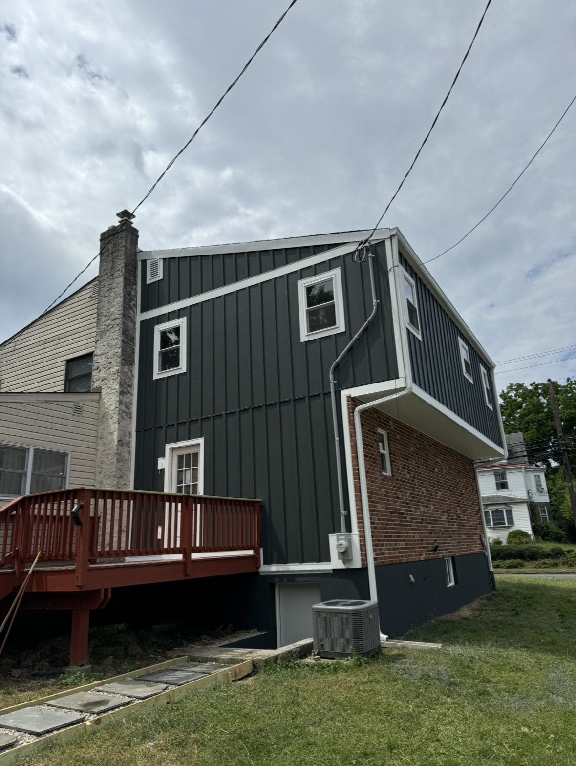 A house with a black siding and a red deck.