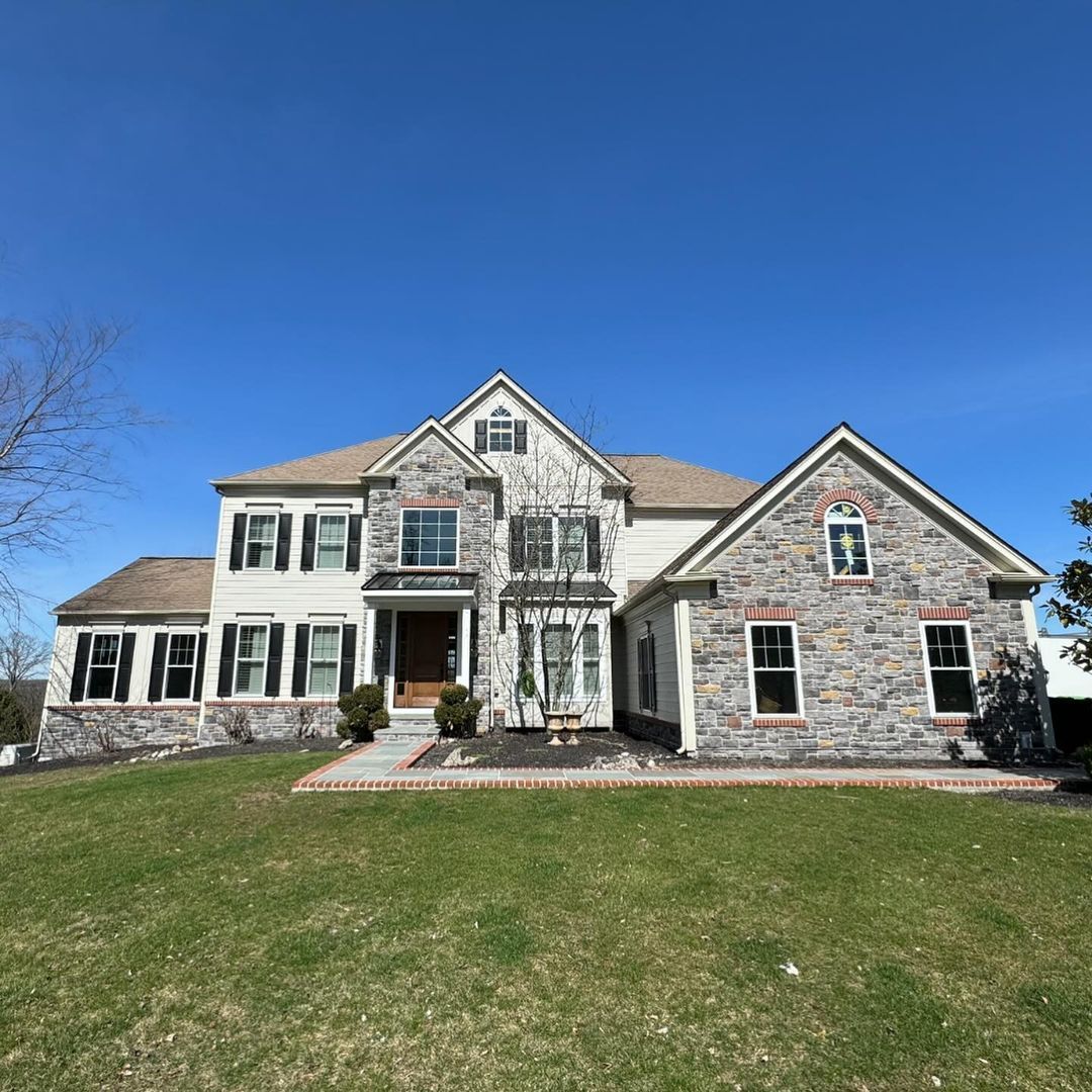 A large stone house with a large lawn in front of it.