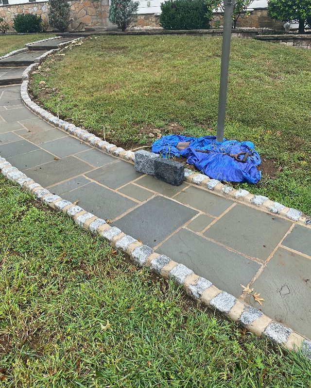 A stone walkway is being built in a grassy area.