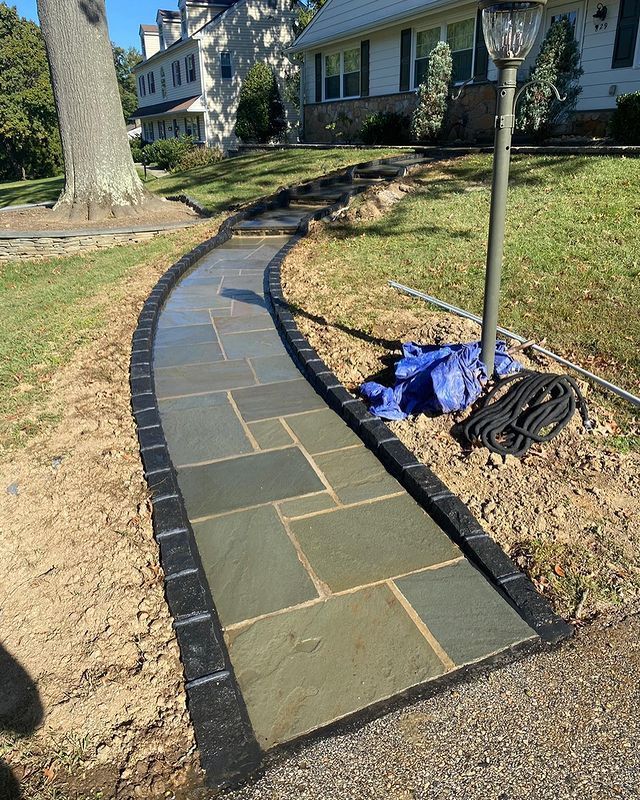 A stone walkway is being built in front of a house.