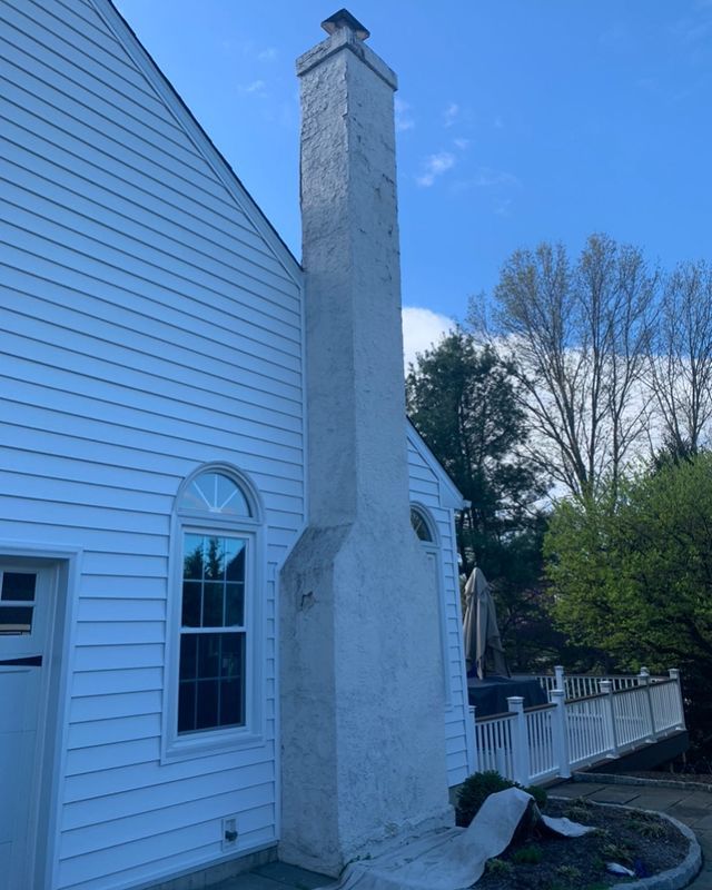 A white house with a chimney on the side of it