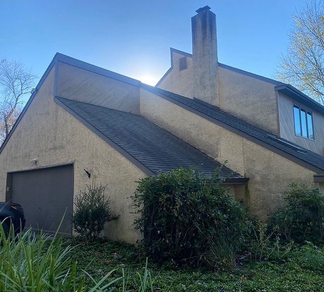 A large house with a garage and a chimney on the roof.