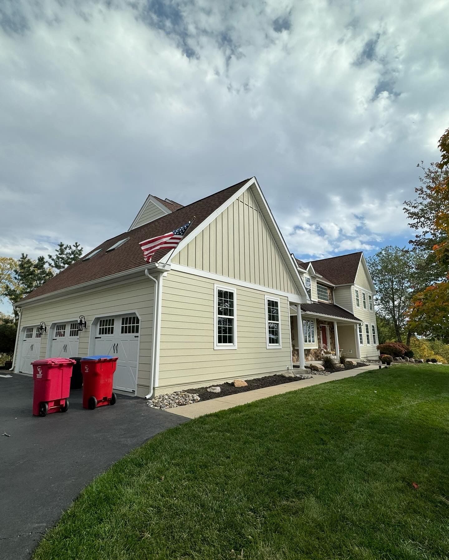 A large house with two red trash cans in front of it.
