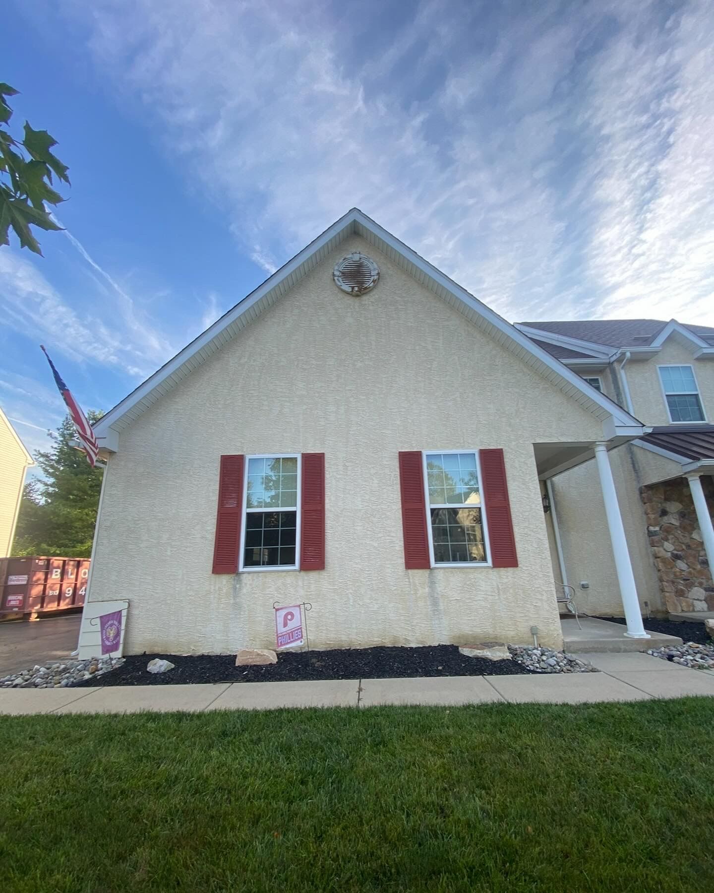 A house with red shutters and a blue sky in the background.