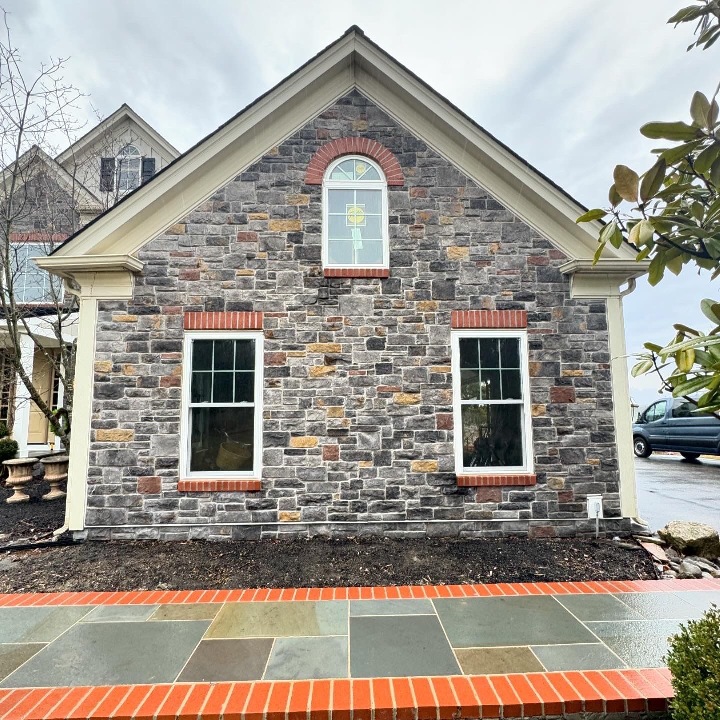 A stone building with two windows and a brick walkway