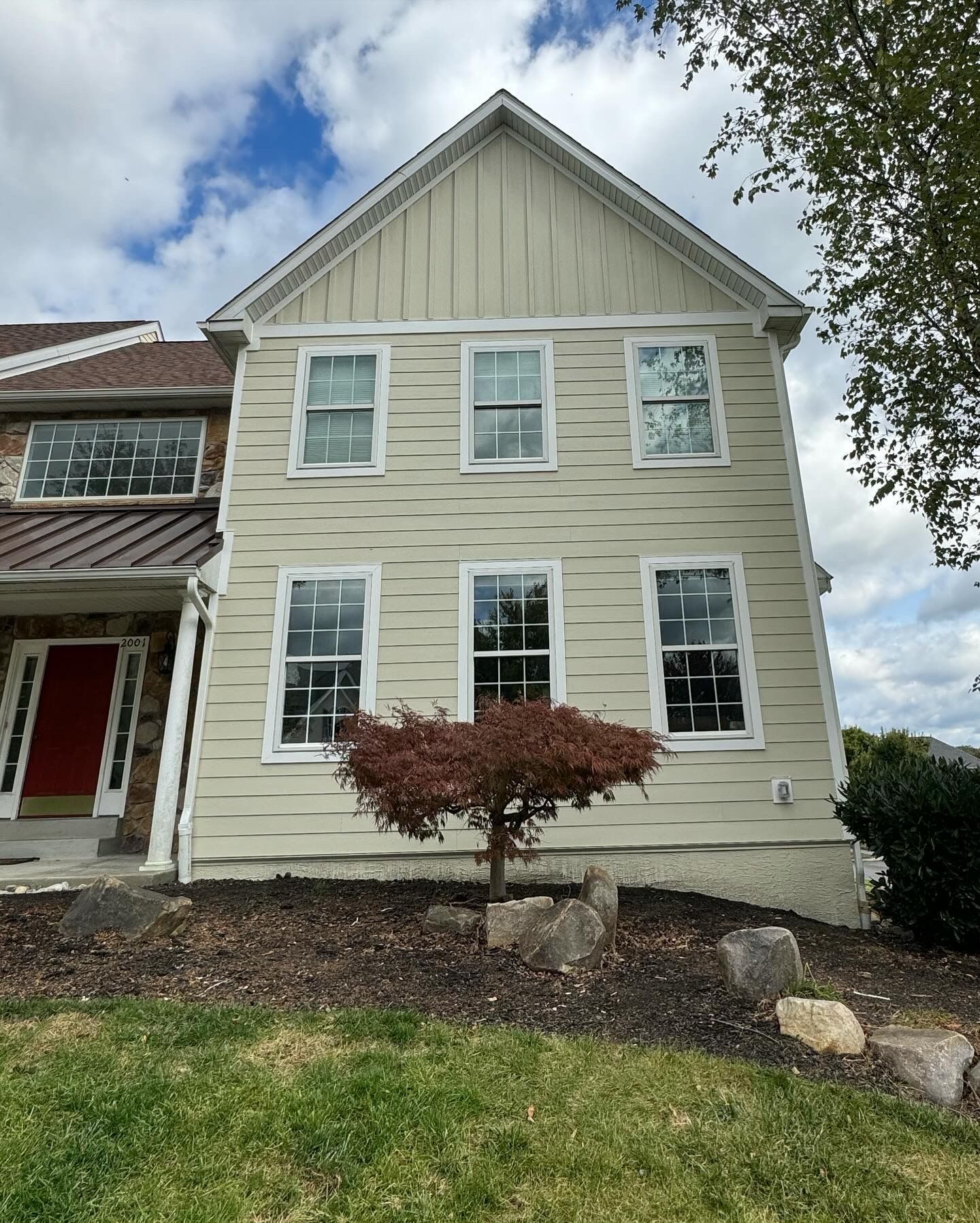A large house with a red door and a tree in front of it.