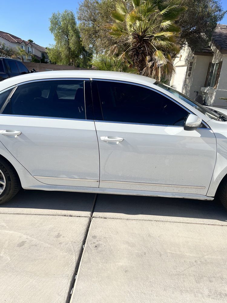 White car with tinted windows parked on concrete driveway in a sunny neighborhood.