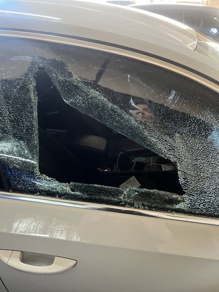 Broken car window; shattered glass on a white car door, revealing interior.