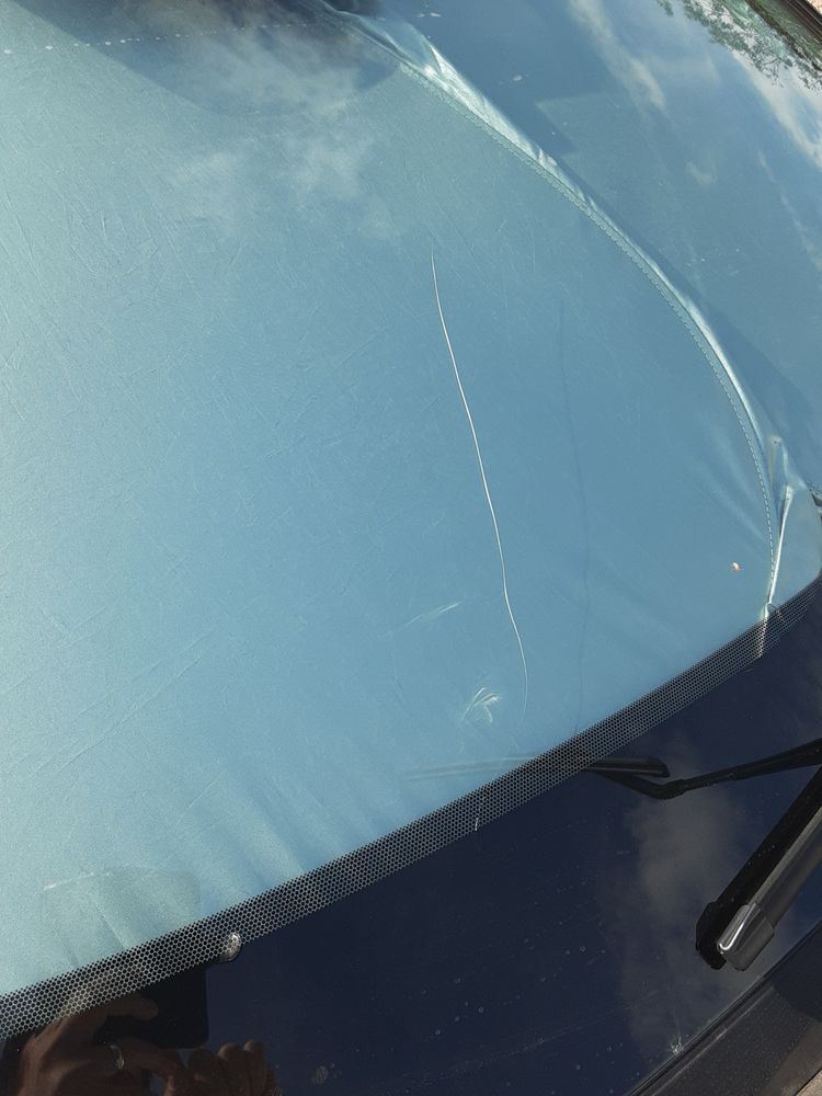 Cracked car windshield with a diagonal crack extending from the top to the center.