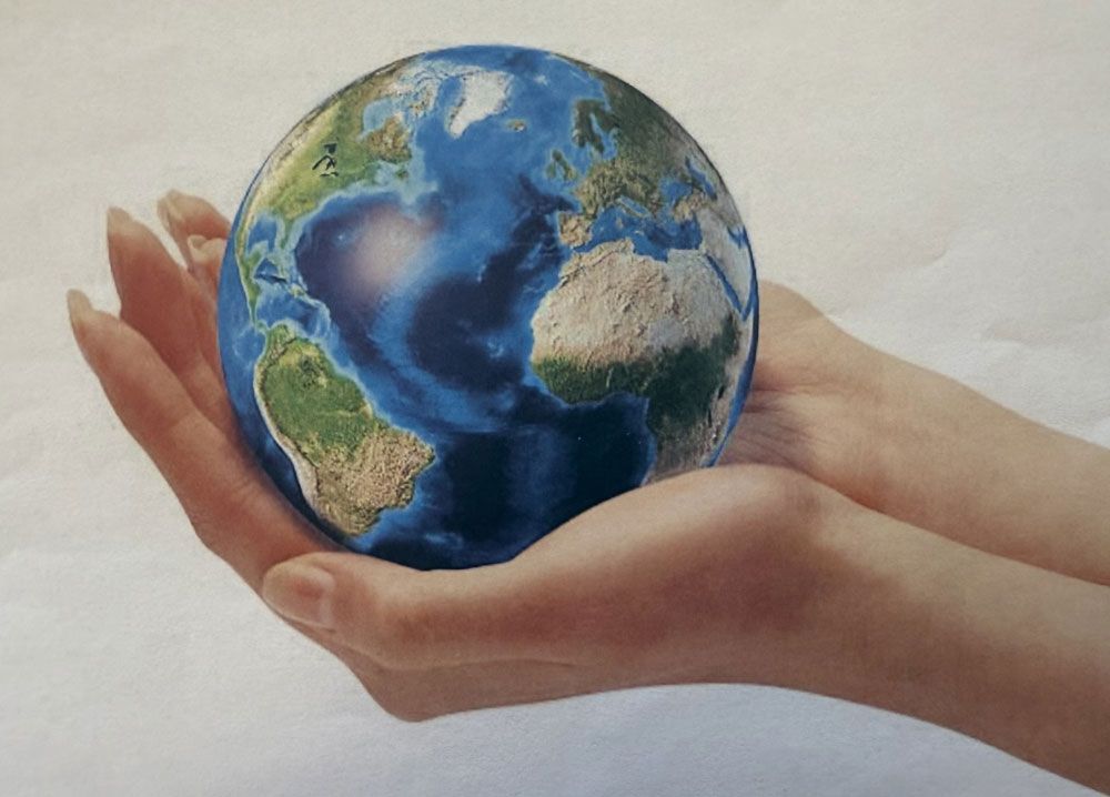 Hands cradling a blue and green Earth globe, white background.