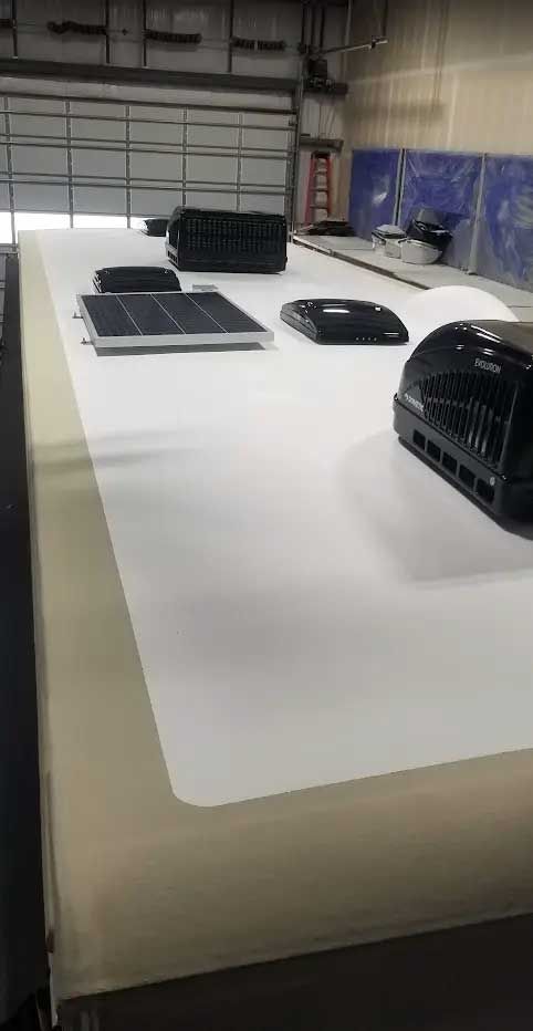 A white roof with solar panels and air conditioners on it in a garage.