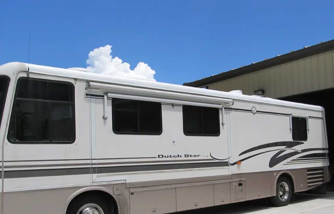 A large white rv is parked in front of a building