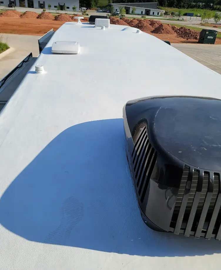 A white roof with a black air conditioner on it.