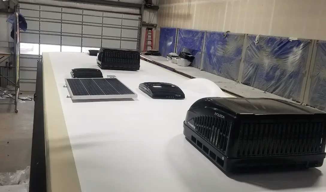 A rv is being built in a garage with solar panels and air conditioners.