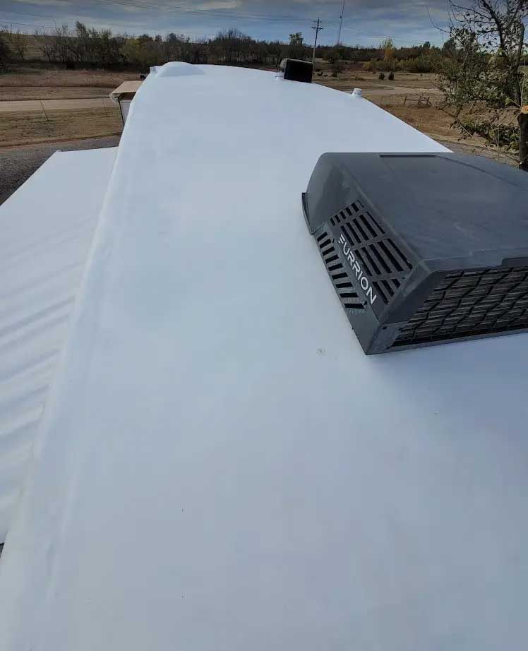 A white roof with a black fan on top of it.