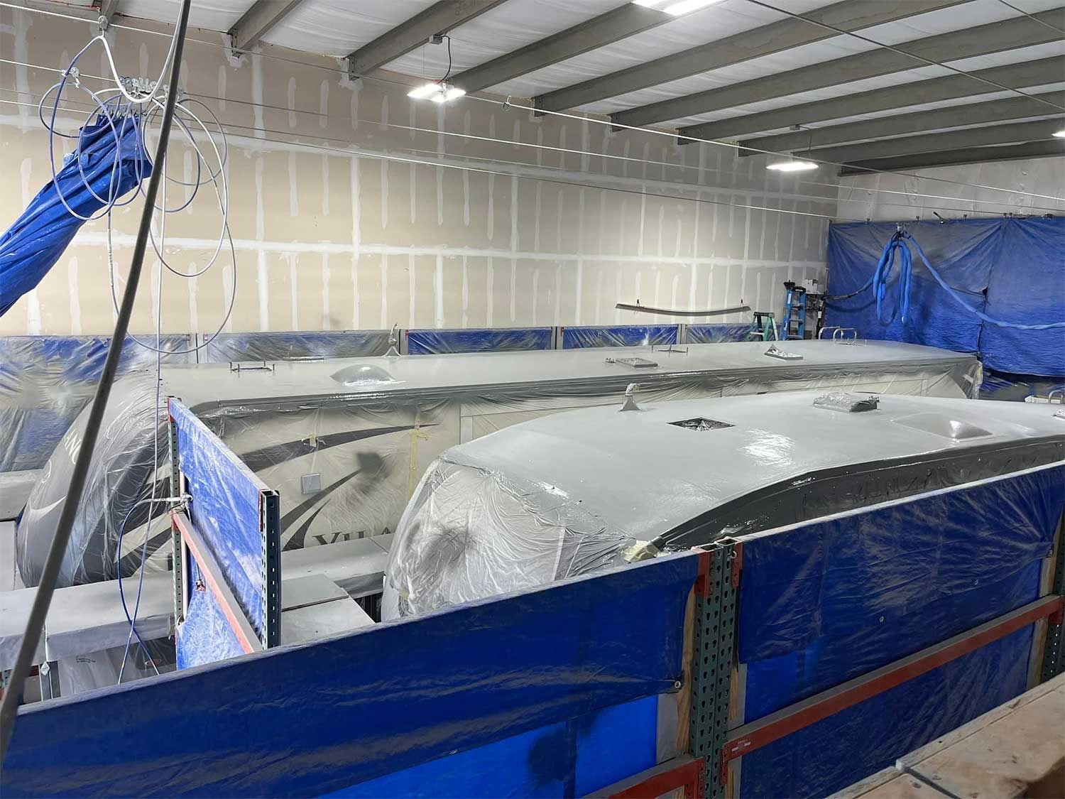 A large white object is sitting inside of a building covered in plastic.