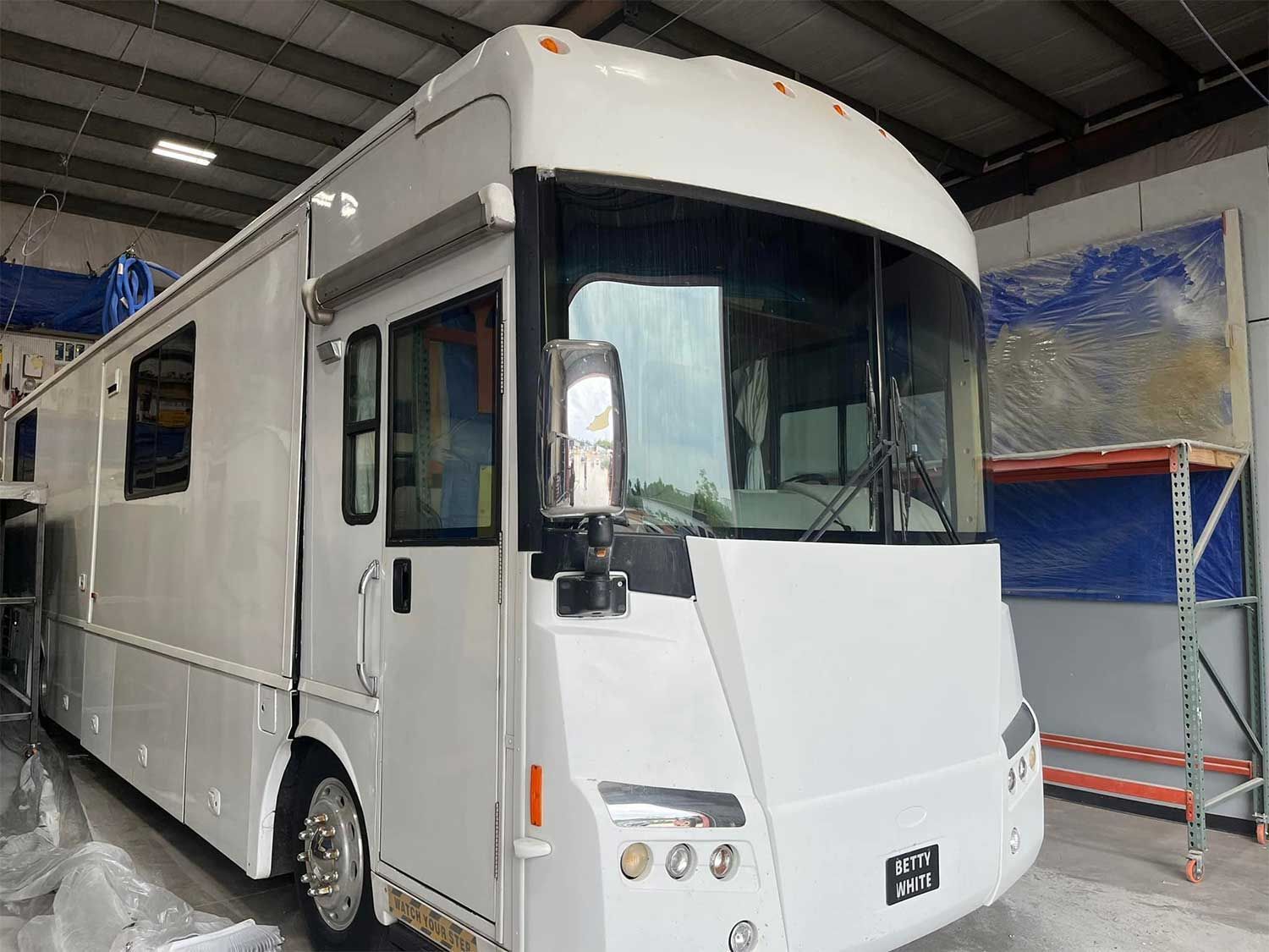 A large white rv is parked in a garage.