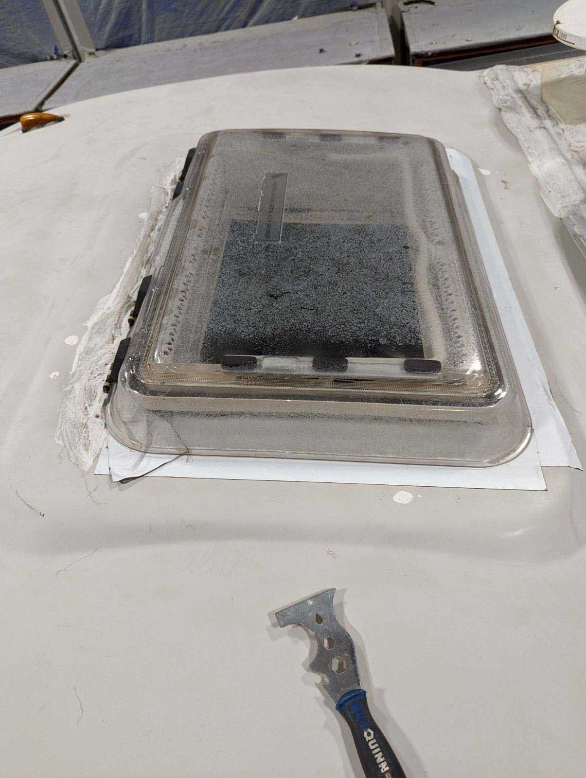 A roof vent is sitting on top of a table next to a wrench.