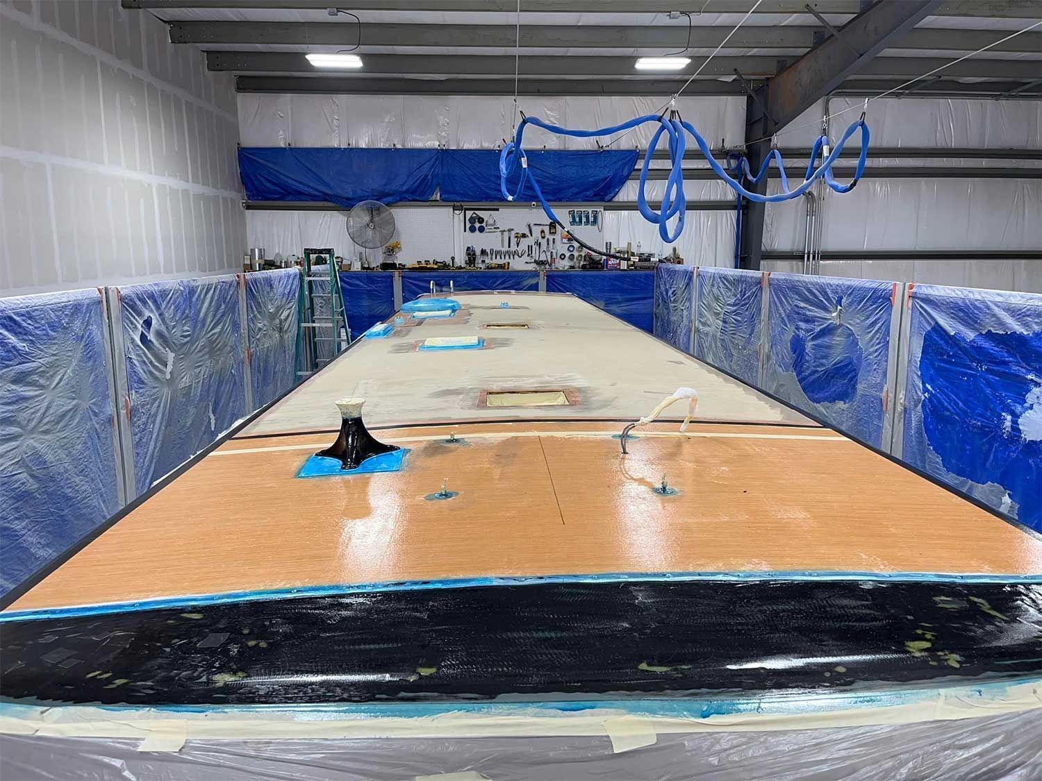 A large wooden table is sitting inside of a building covered in plastic.