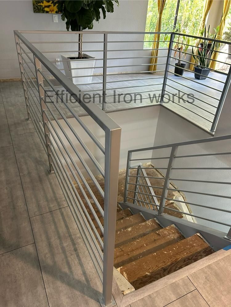 A modern interior with a metal railing alongside a staircase, light gray tones, and visible 