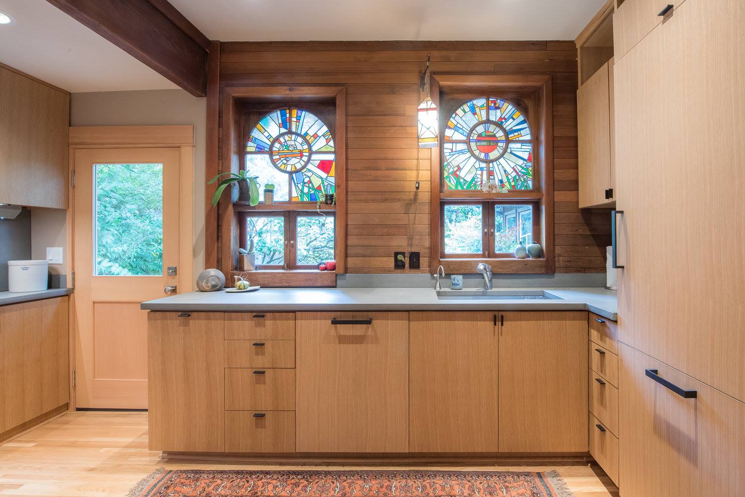 A kitchen with wooden cabinets and a stained glass window.