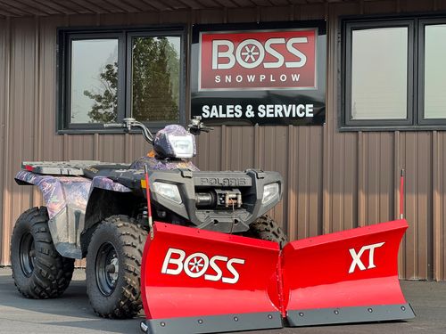 ATV with red BOSS snowplow parked outside a BOSS sales and service building