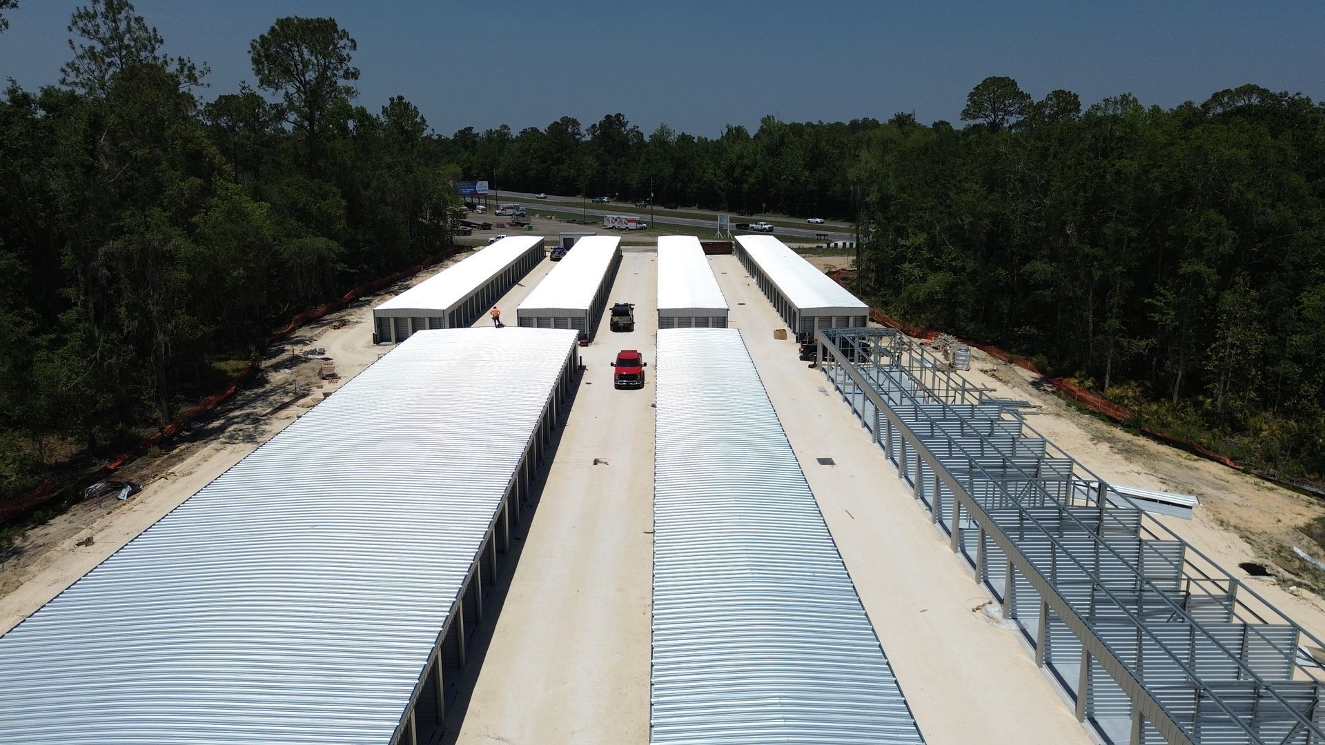 Outdoor testing track with long silver lanes, a red vehicle, and trees on both sides