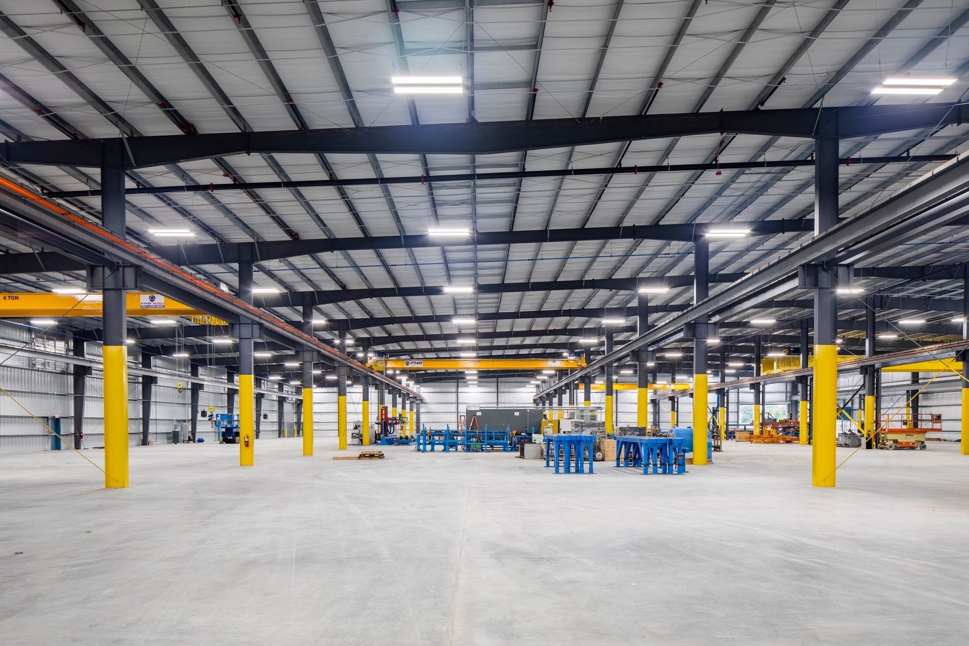 Empty industrial warehouse interior with yellow support columns and overhead steel beams