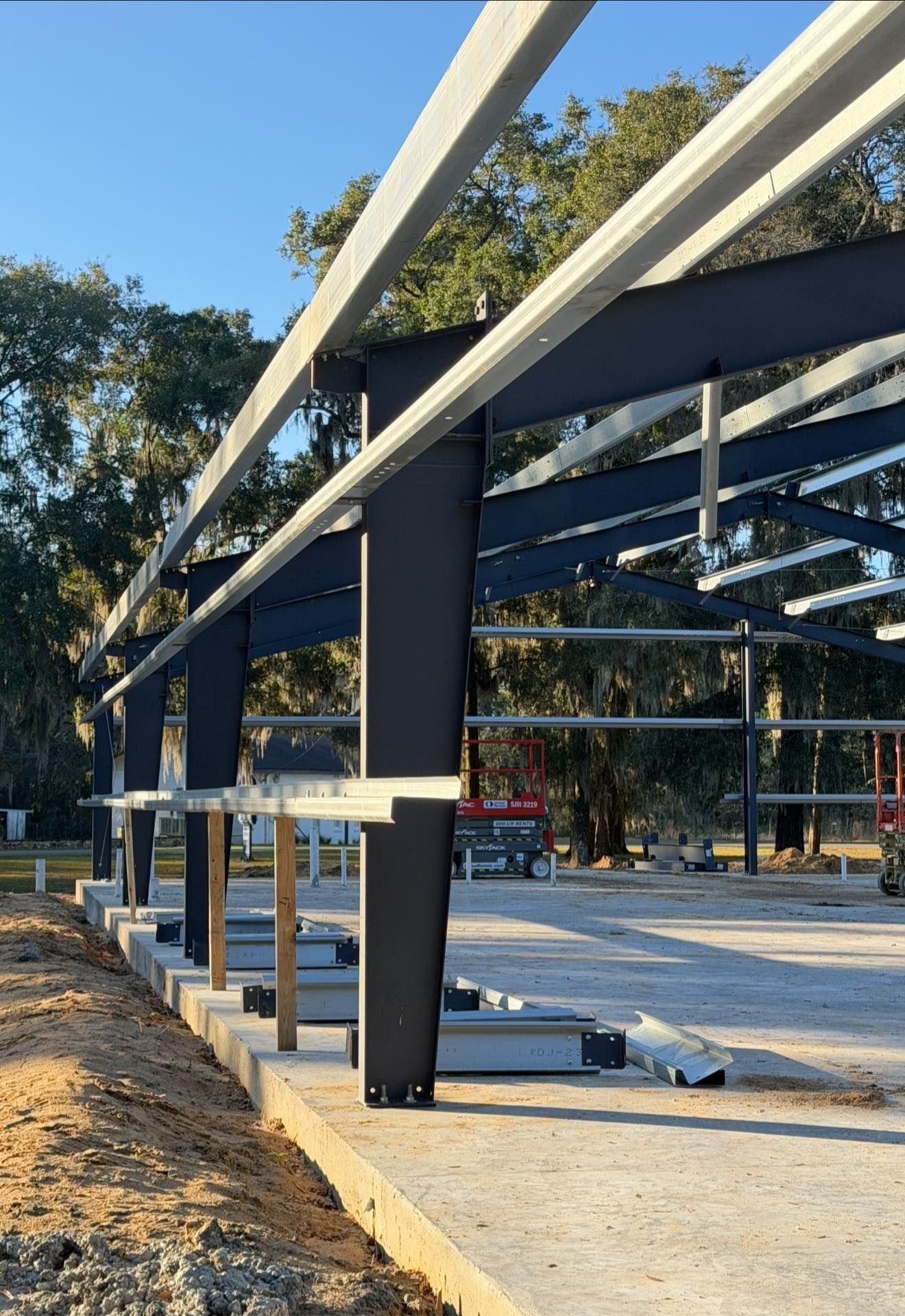 Outdoor construction site with steel beams and concrete slab under a clear blue sky.