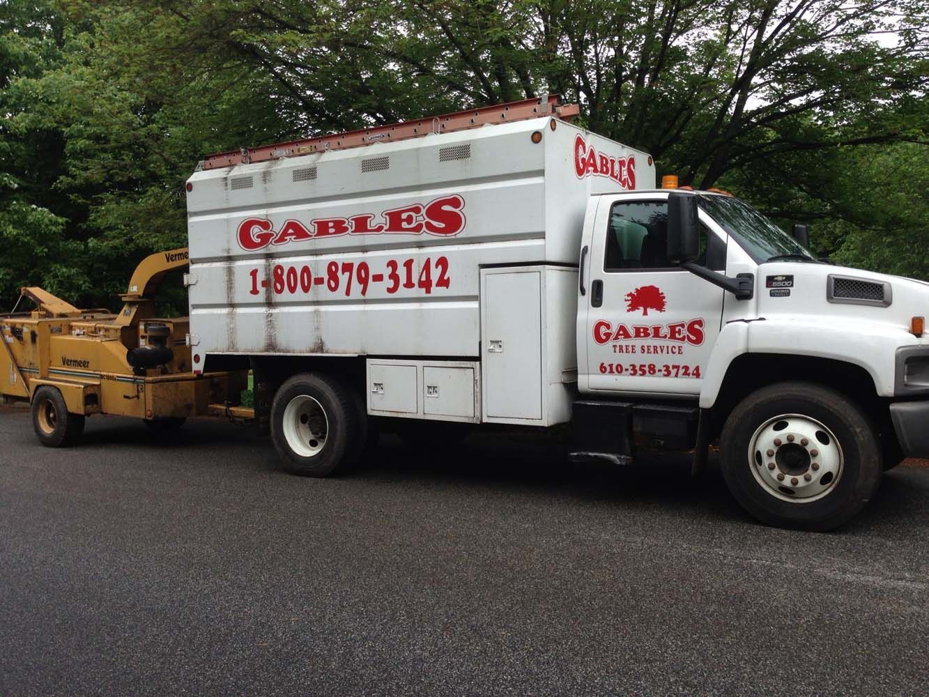 A white Gables tree service truck parked on asphalt with a yellow wood chipper attached to the rear.