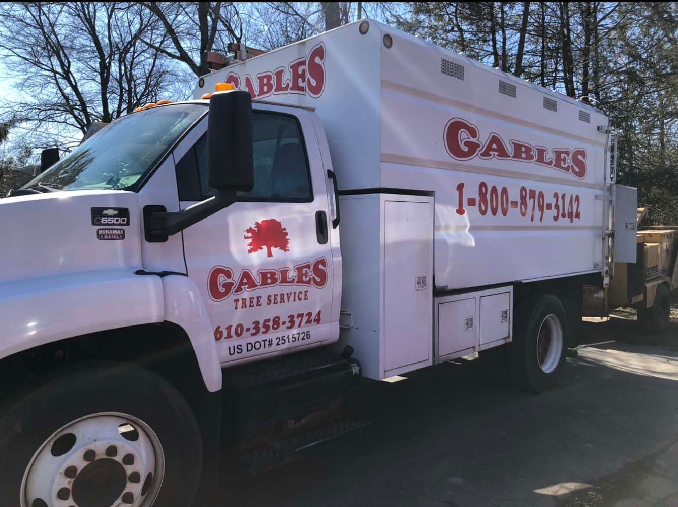 A white Gables Tree Service utility truck parked outdoors with the company logo and phone numbers printed on the side.