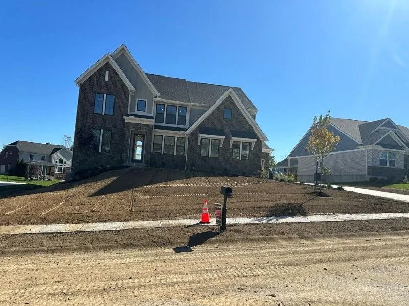 New house under construction with a front yard and dirt road in the foreground