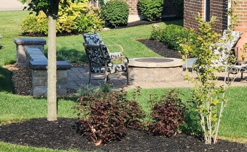 Landscaped front yard with patio chairs, stone steps, shrubs, and a mulched flower bed.