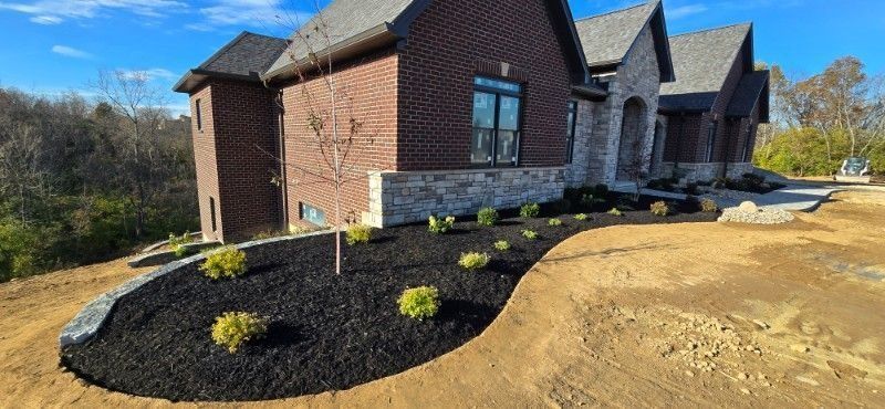 New brick house exterior with dark mulch landscaping and a curved walkway under a blue sky